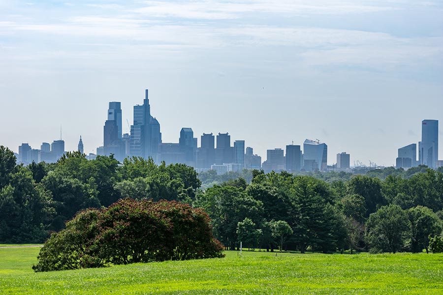 About Our Agency - Misty View of Philadelphia Skyline as Seen From a Distance in a Green Park
